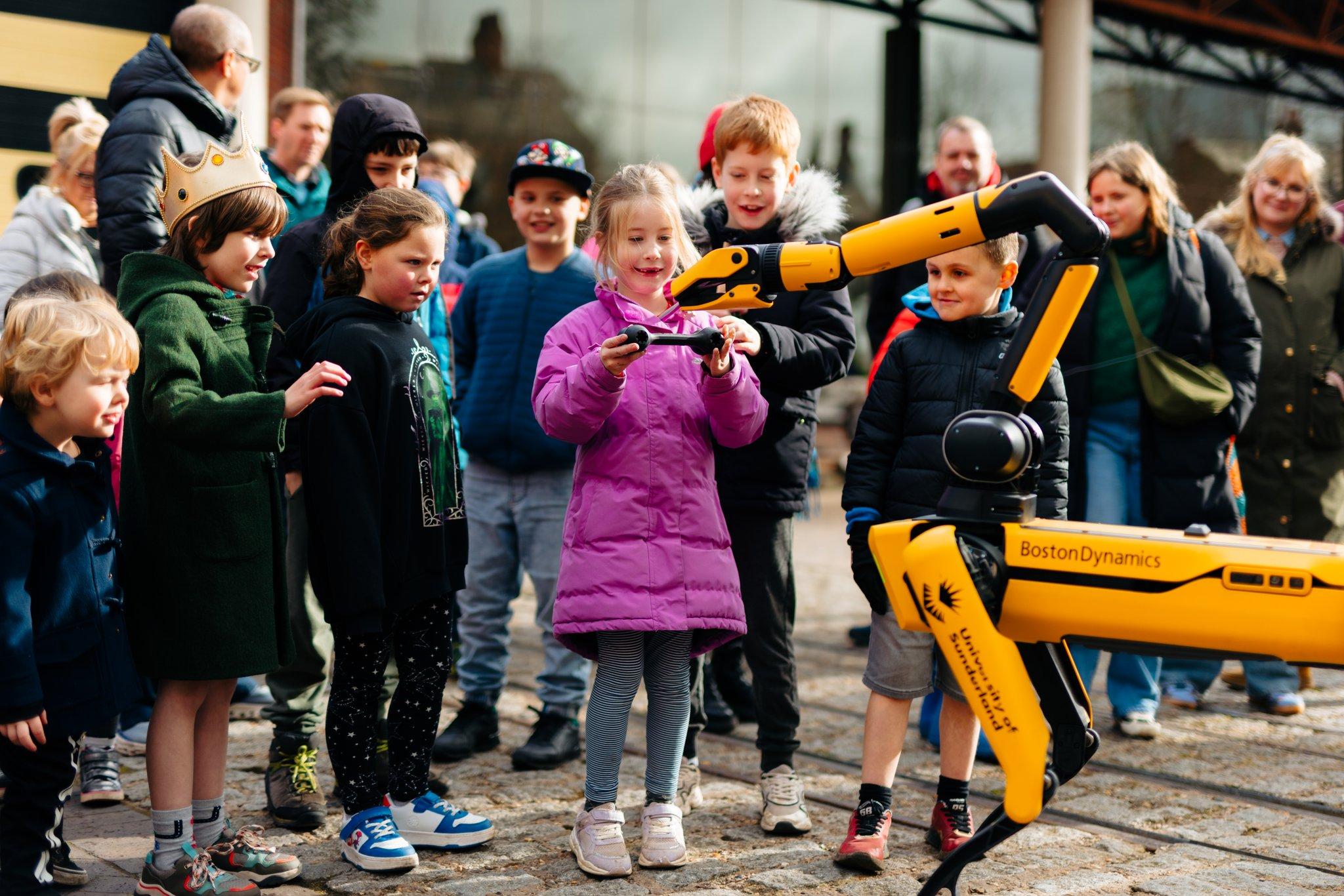 A group of people looking at a large yellow robot dog