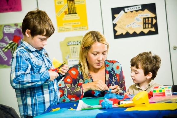A woman helping two children with crafts
