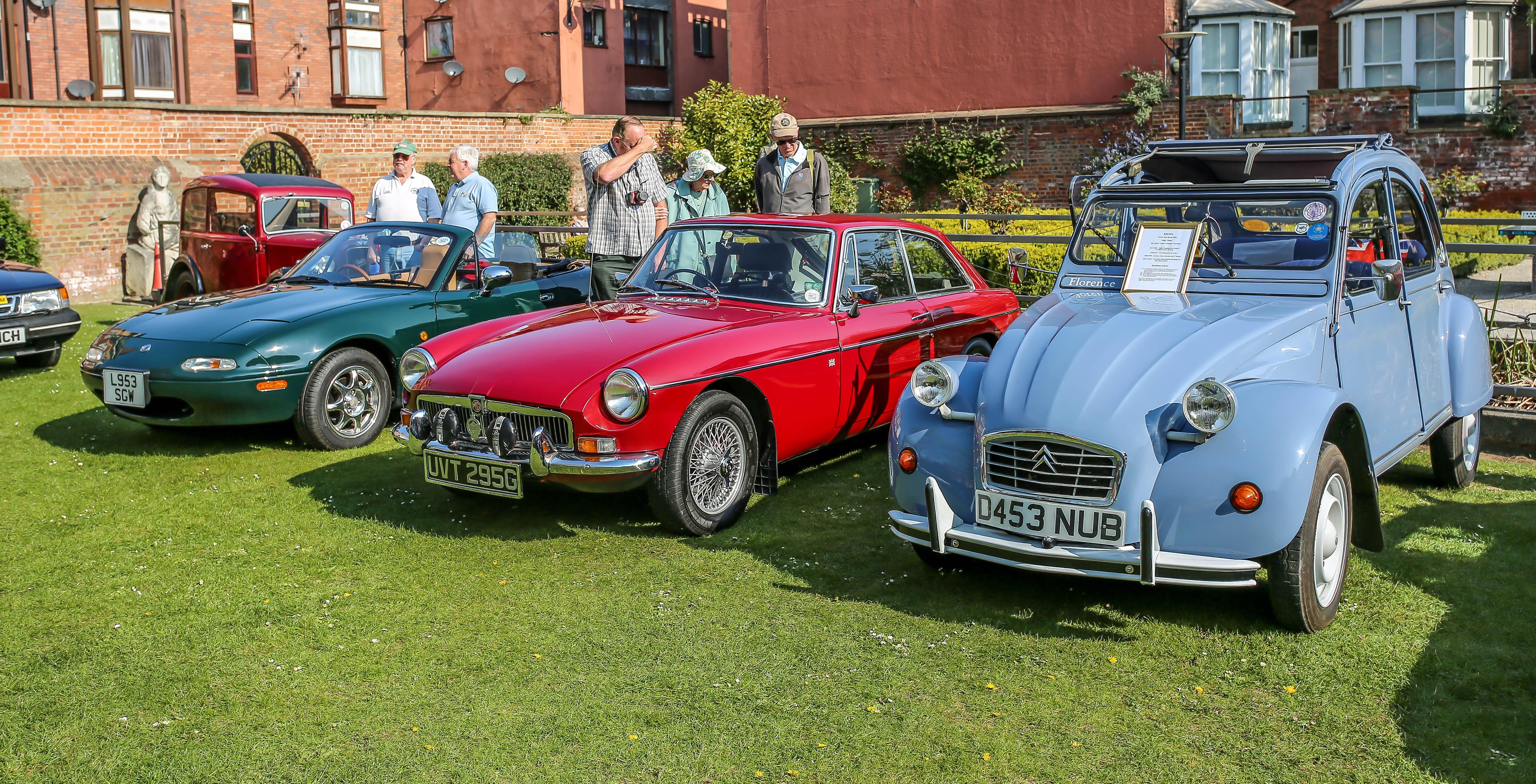 3 vintage cars on a grassed area