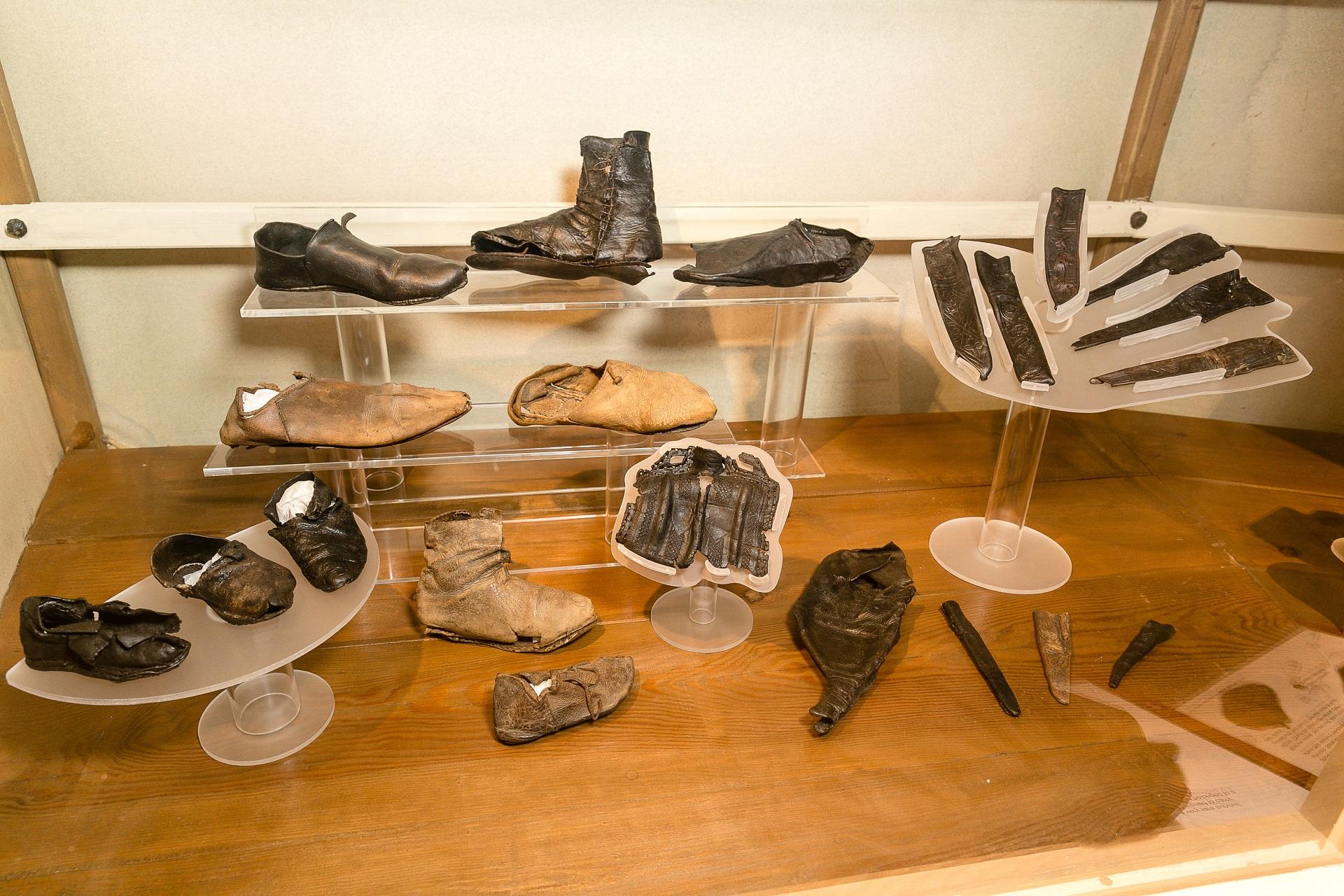 Medieval leather objects in a glass display case.