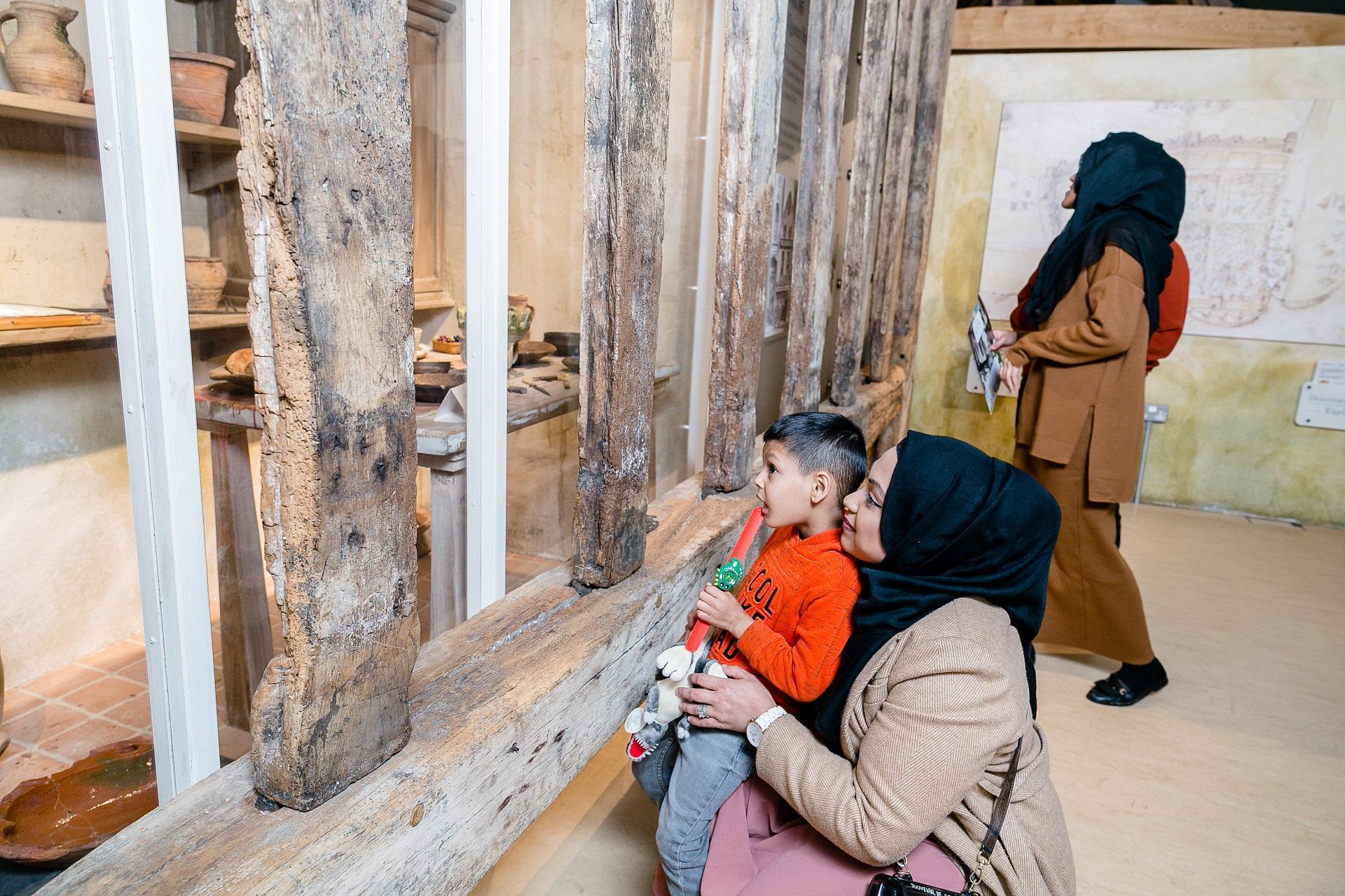 A woman and a child looking at objects in a display case.