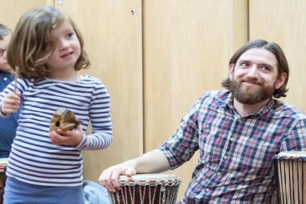 A child and a man playing a drum