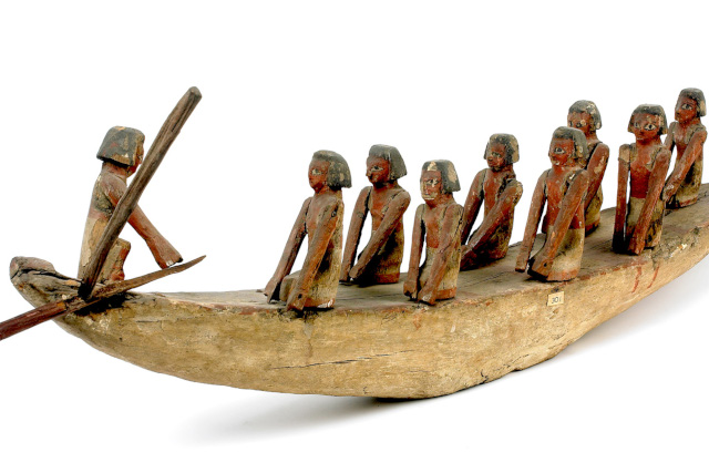 A wooden boat with carved wooden figures sat on top of it.