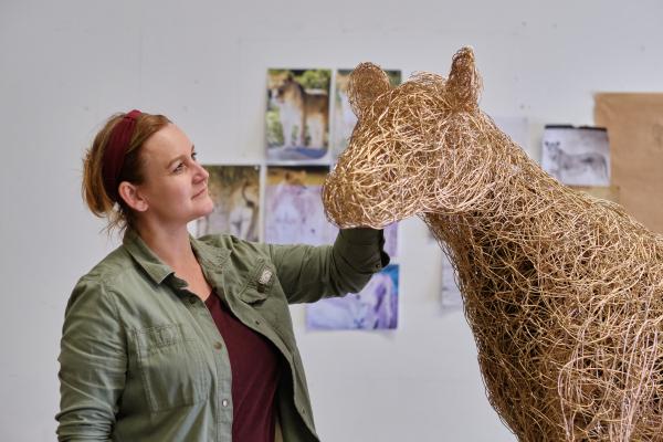 A woman looking at a sculpture of a horse