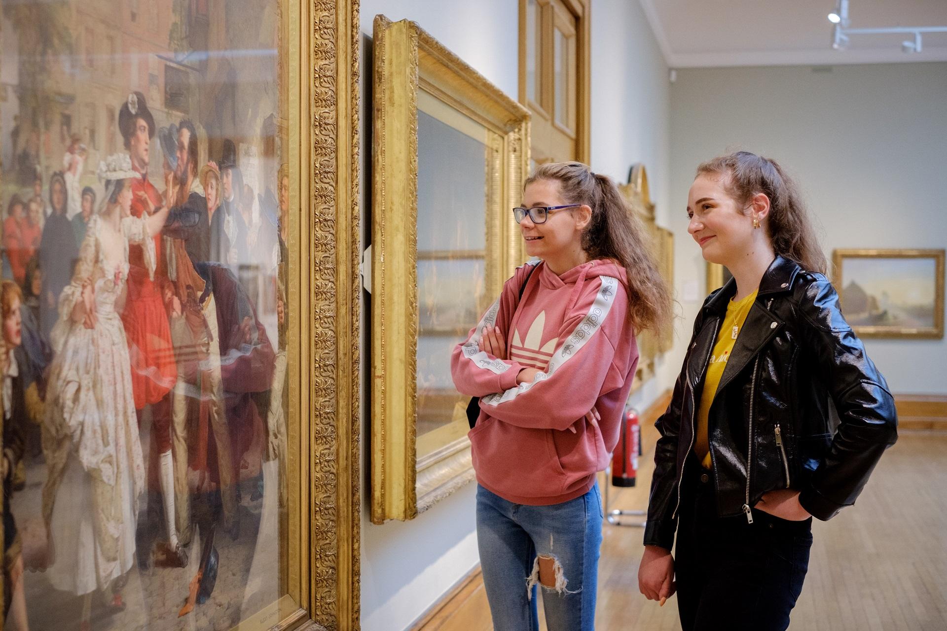 Two women looking at a large painting in an art gallery.