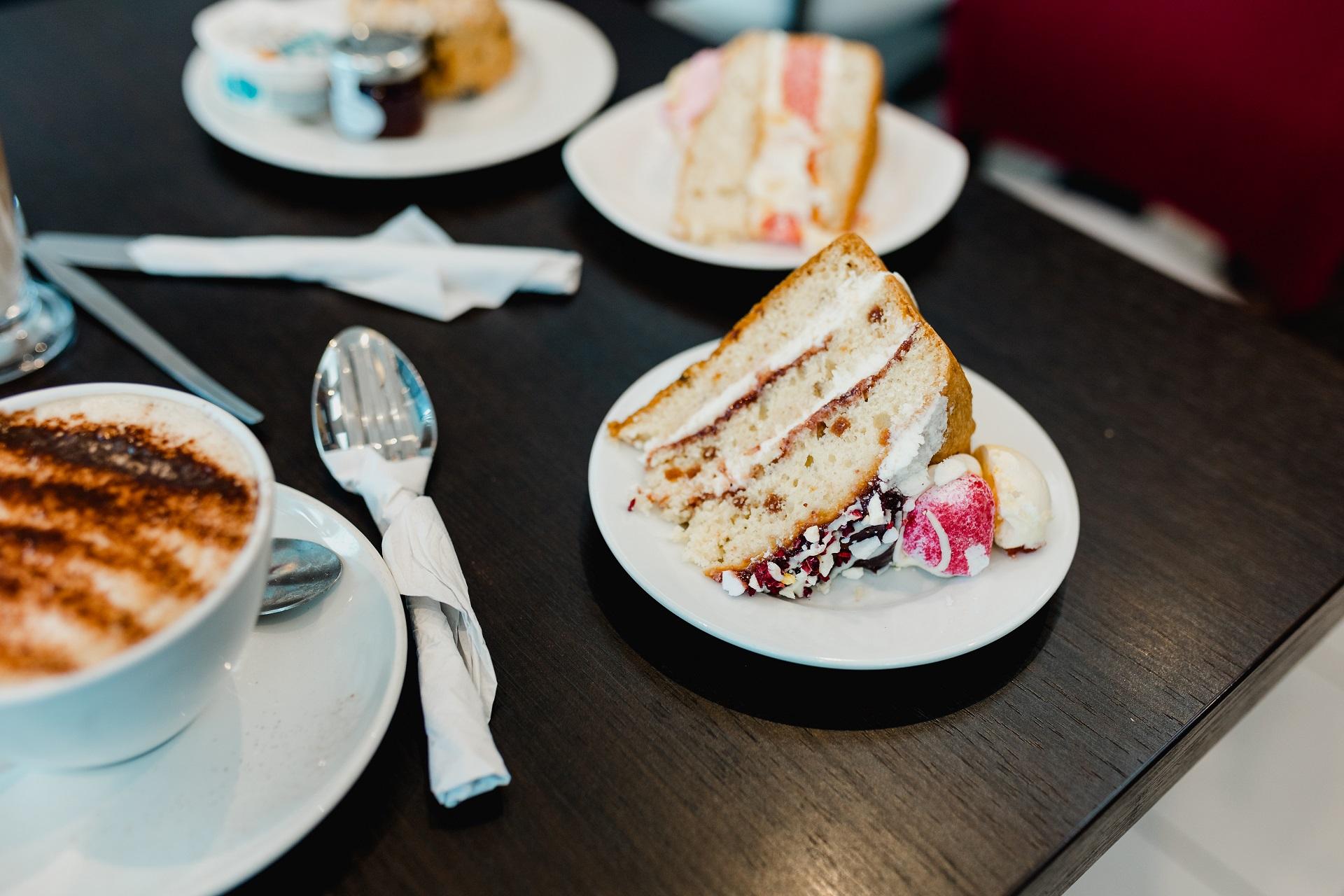 Pieces of cake and a coffee on a black table.