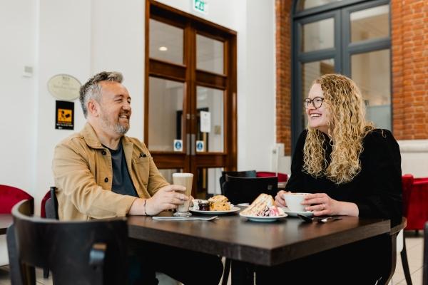 A man and a woman sat having coffee and cake in a cafe.