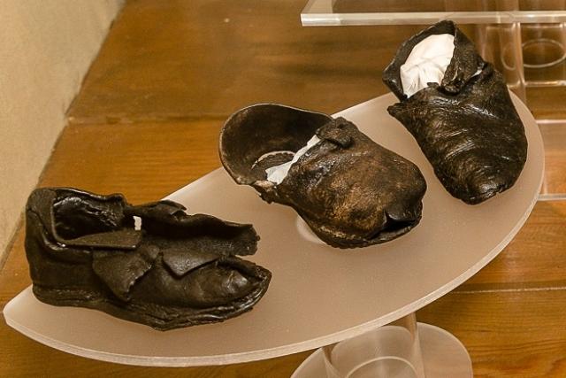 Three medieval leather shoes in a glass display case