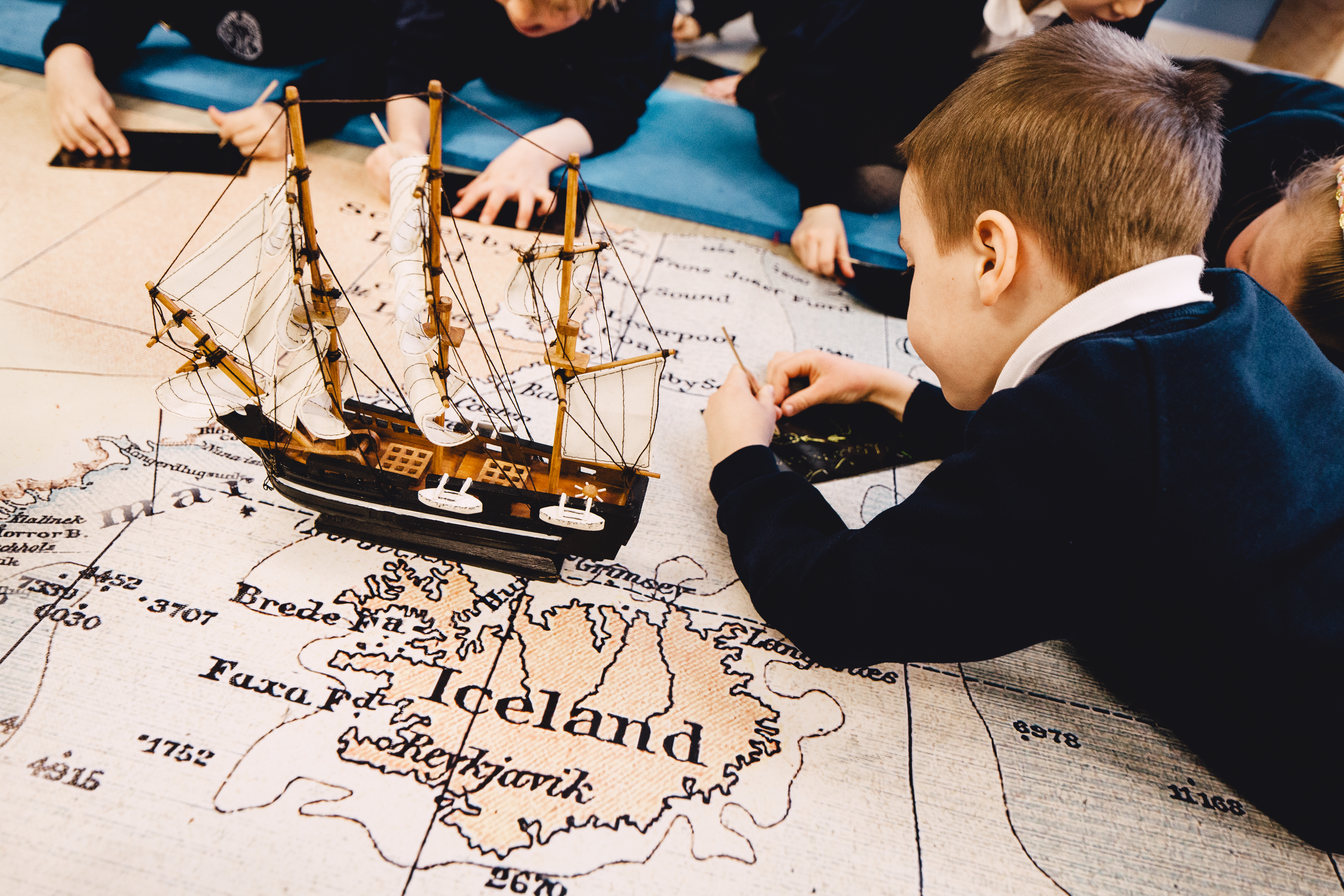 A child is looking at a map of the Arctic ocean beside a model of a ship.