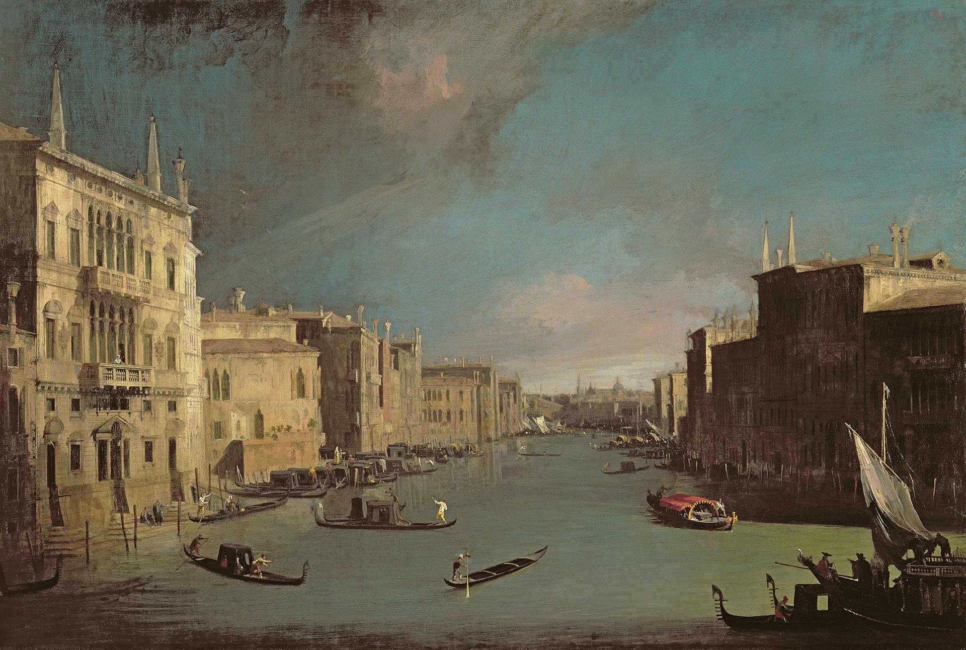 A painting of a canal in Venice. Buildings line the canal and there are boats on the water