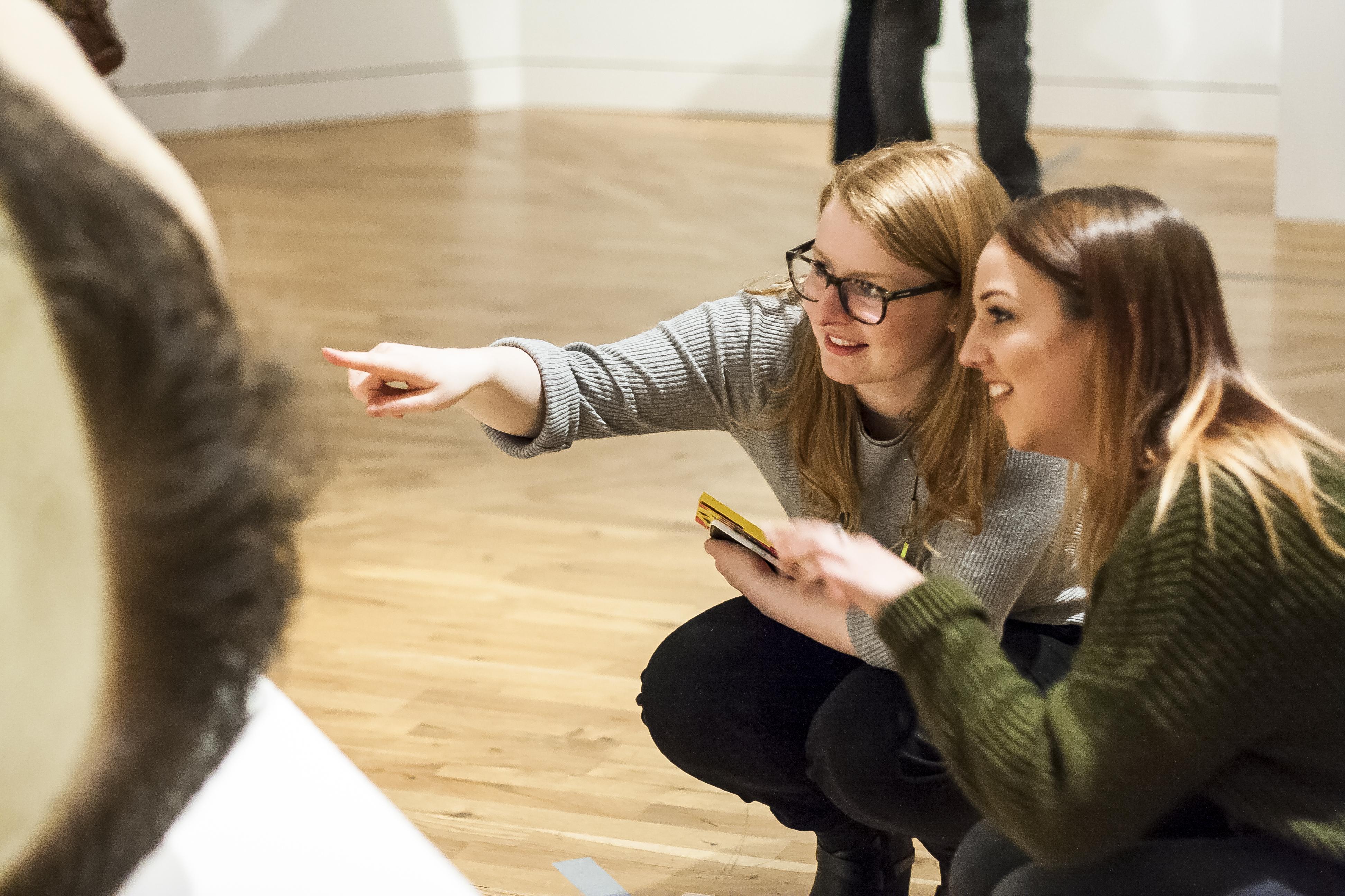 Two women looking at a sculpture in an art gallery.