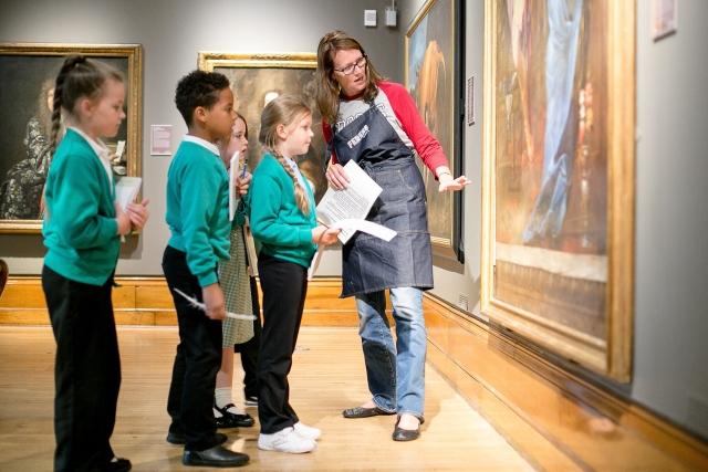 A woman and three children looking at a painting in an art gallery.