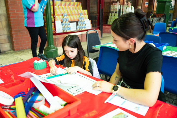A mother and daughter sat at a table working on crafts together