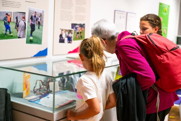 Lionesses of Hull - multigenerational visitors looking into a glass object box