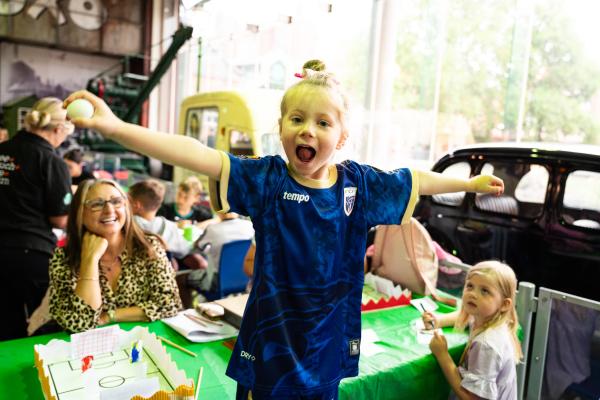 a girl visiting does a goal celebration with outstretched arms