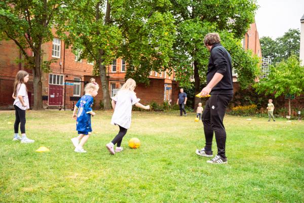 young girls playing football outside on grass