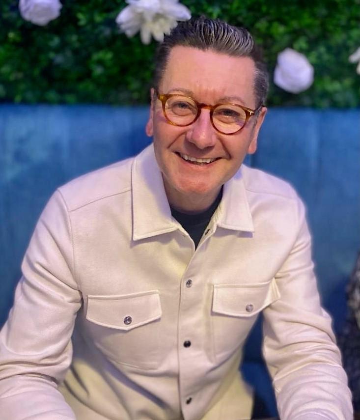 A white man with dark hair wearing glasses