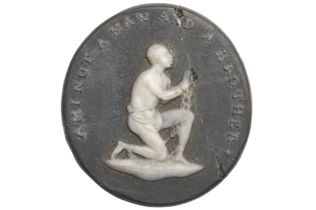 A metal medallion with a kneeling man on it.