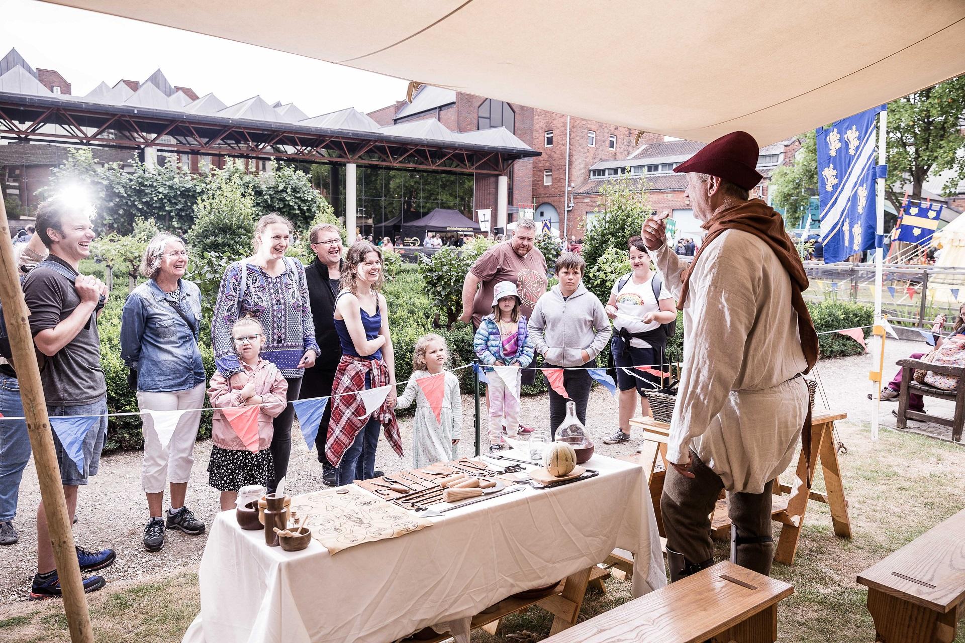 A man dressed in medieval costume giving a display to a crowd of people.