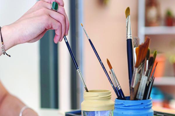 A hand using paint brushes