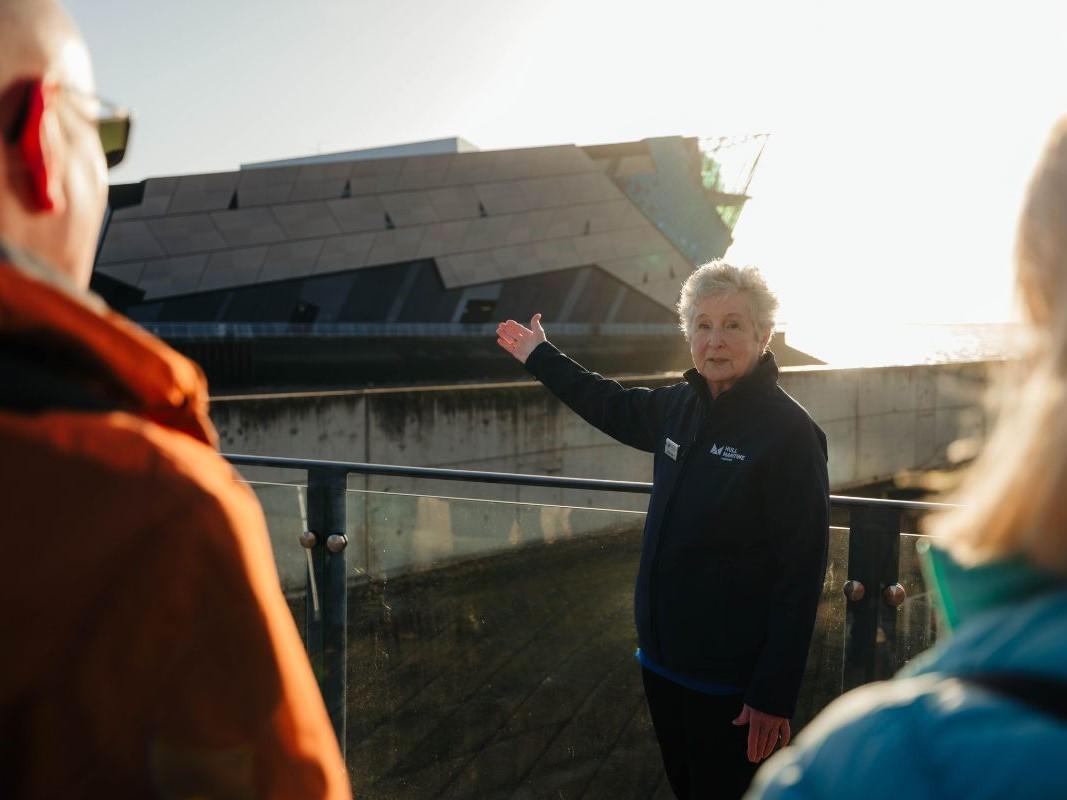 A woman pointing at a large building while talking to a group of people