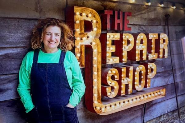 Lucia Scalisi stood in front of a lit up sign writing The Repair Shop