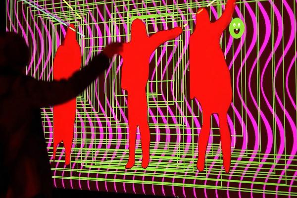 A silhouette person dancing in front of an interactive light display/