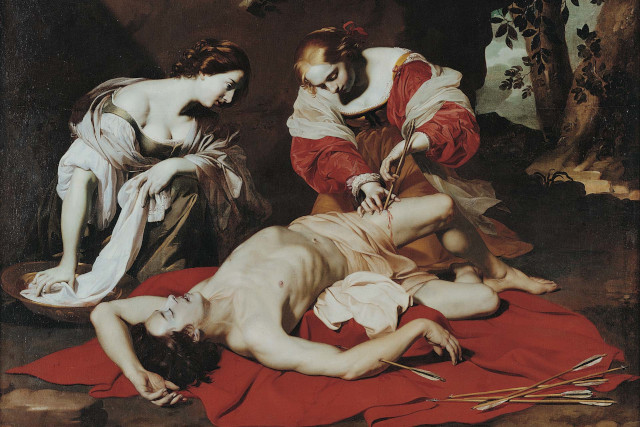 A painting of a man laid on the ground with an arrow in his leg. Two people are knelt over him and one is holding the arrow.