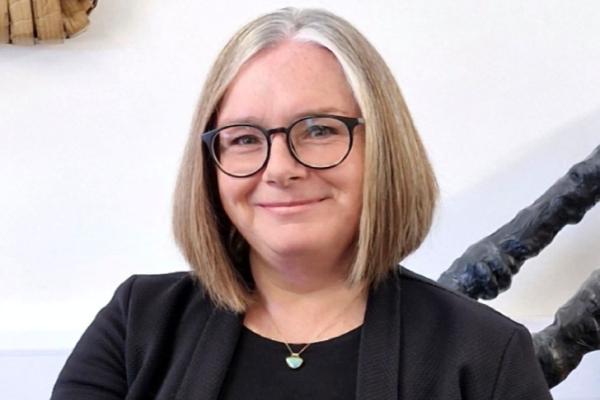 A portrait image of a woman, She has short hair and is wearing glasses