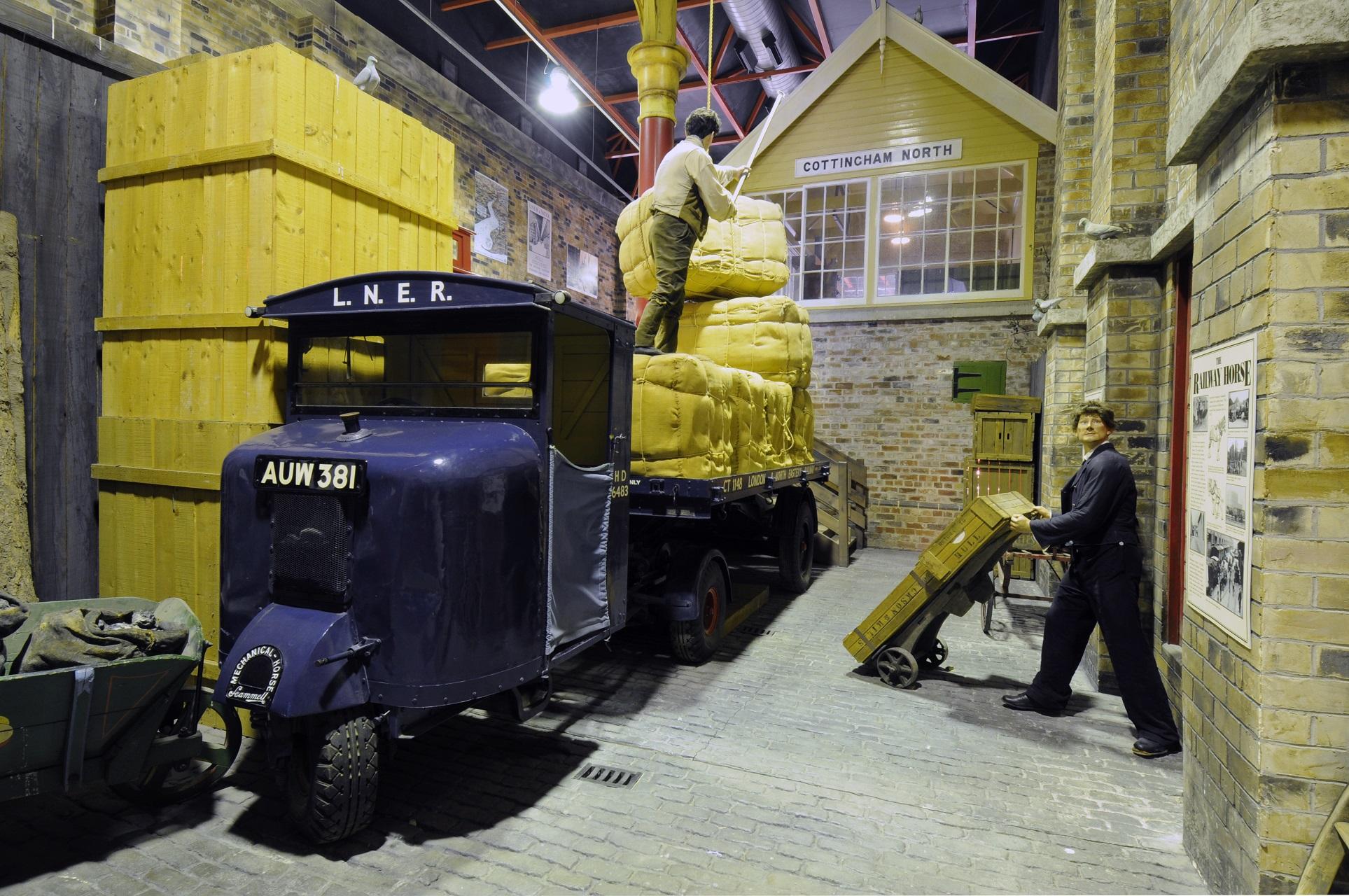 A railway scene in a museum with a three wheel van and a signal box behind it.
