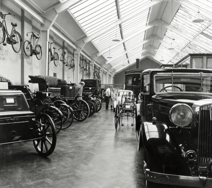 A black and white photograph of vintage cars in a museum