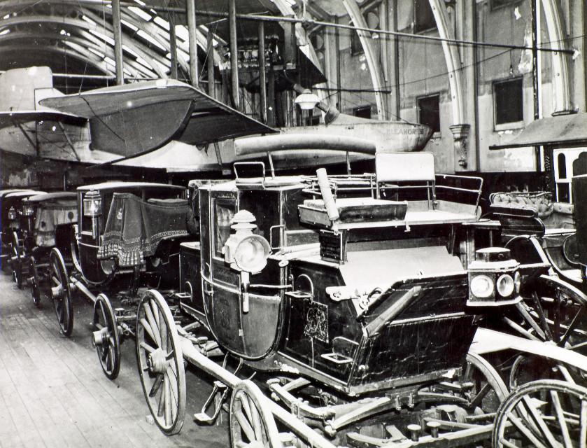 A black and white photograph of horse drawn coaches in a museum