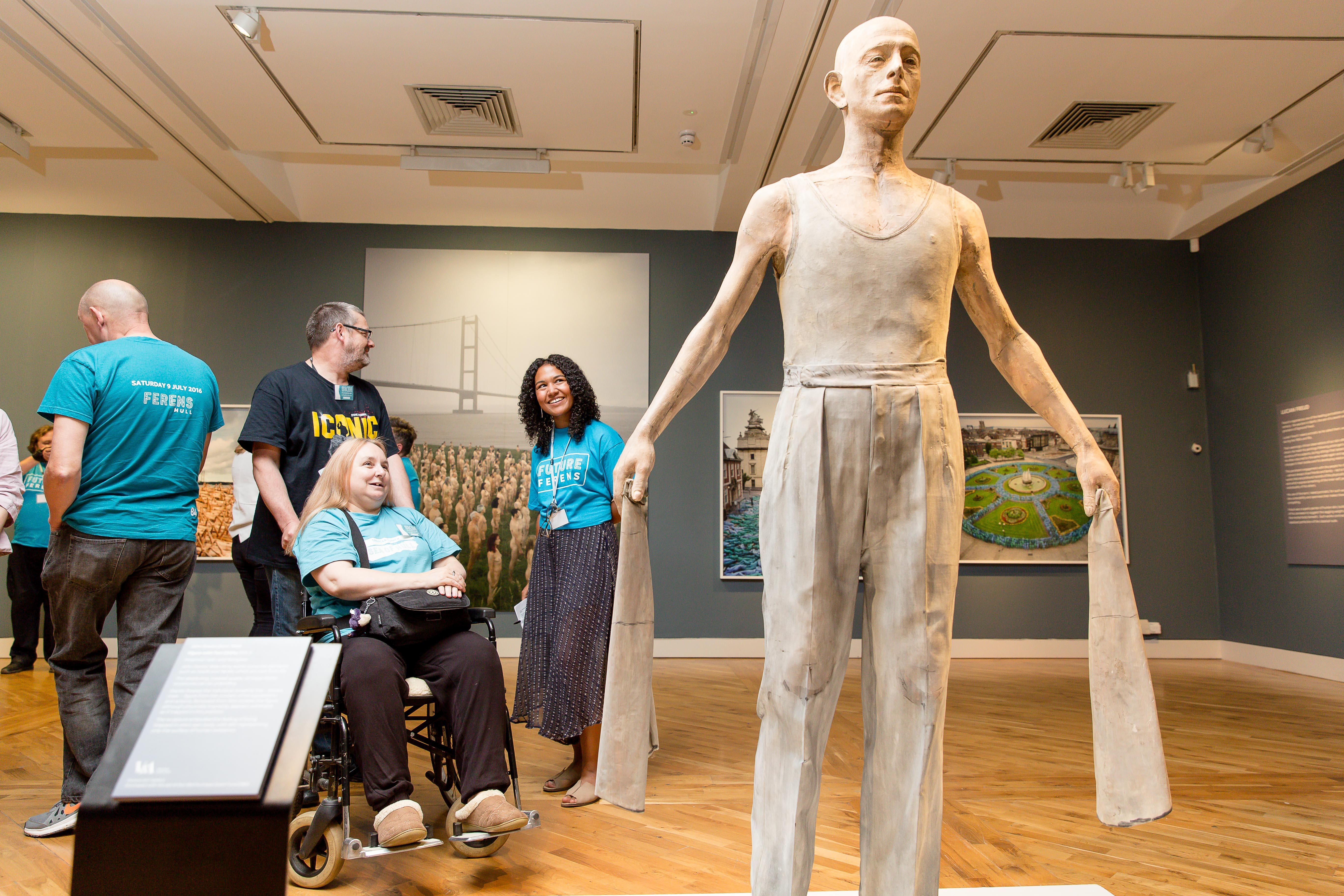 Four people looking at a sculpture of a man.