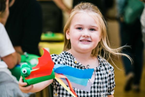 A girl holding a multicoloured paper dragon